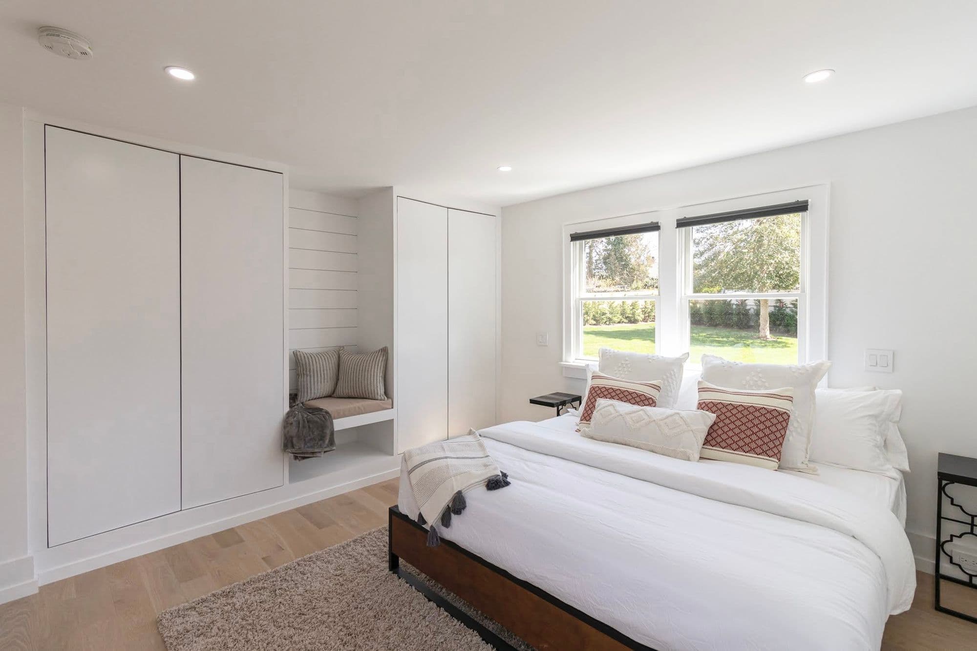 Bedroom with built-in reading nook, shiplap closet doors, and garden views