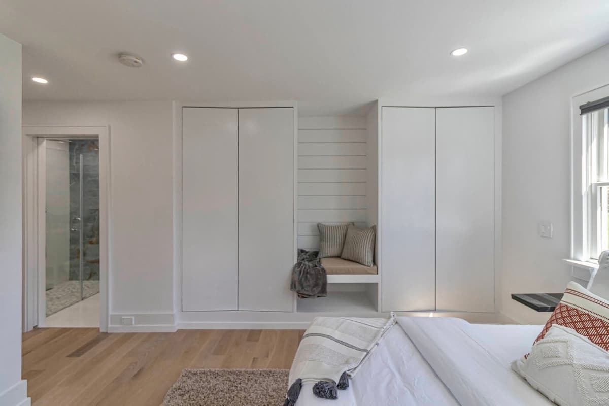 Bedroom with ensuite bathroom, built-in reading nook, and custom painted shiplap closets
