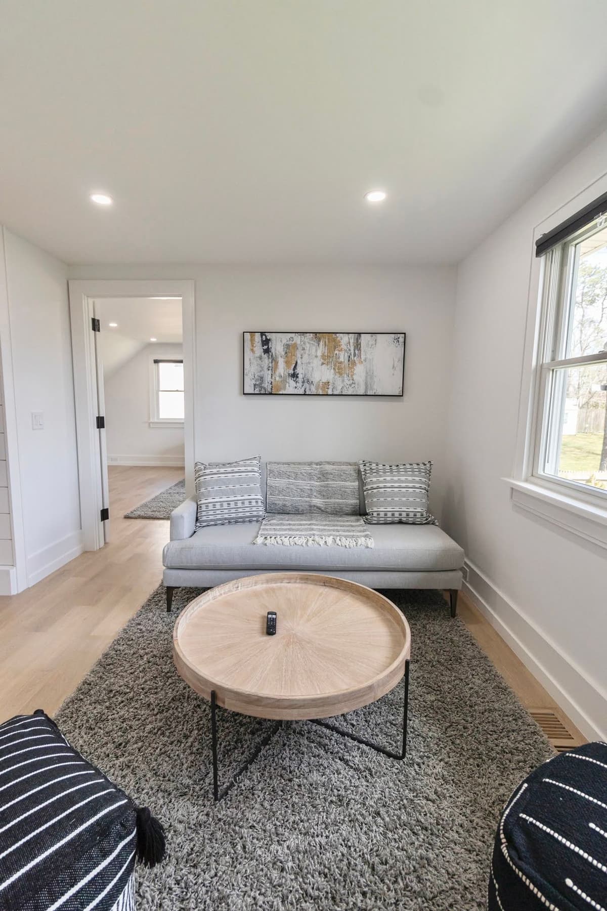 Cozy sitting room with freshly painted white walls, gray sofa, and abstract artwork