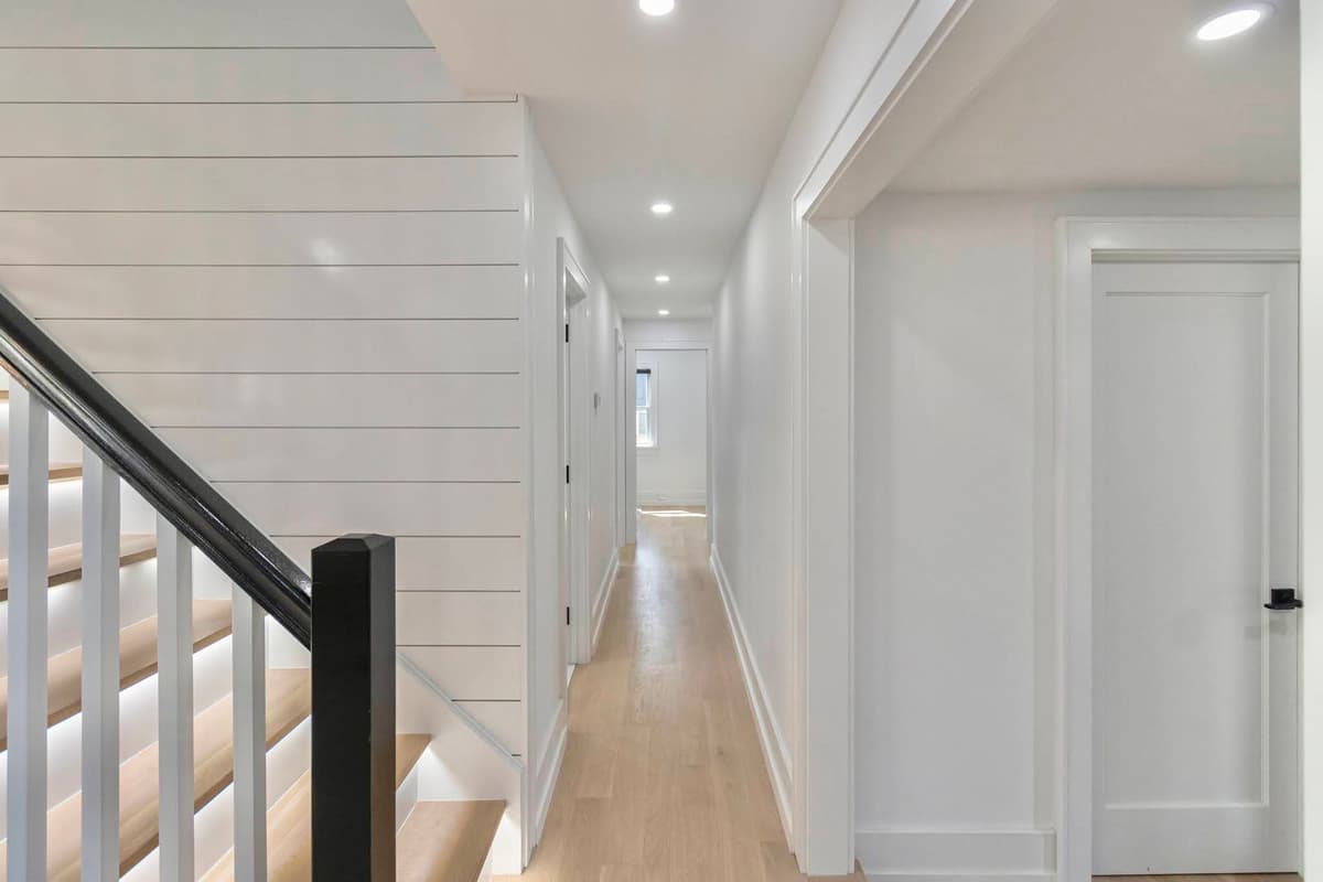 Hallway with painted white shiplap wall, precision-finished trim, and recessed lighting