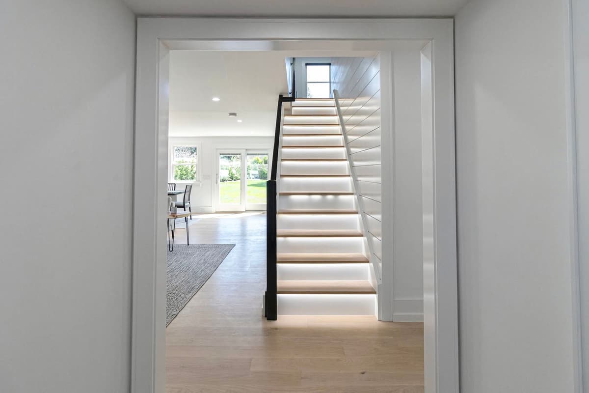 LED-lit staircase with painted white risers and trim, viewed through a cleanly finished doorway
