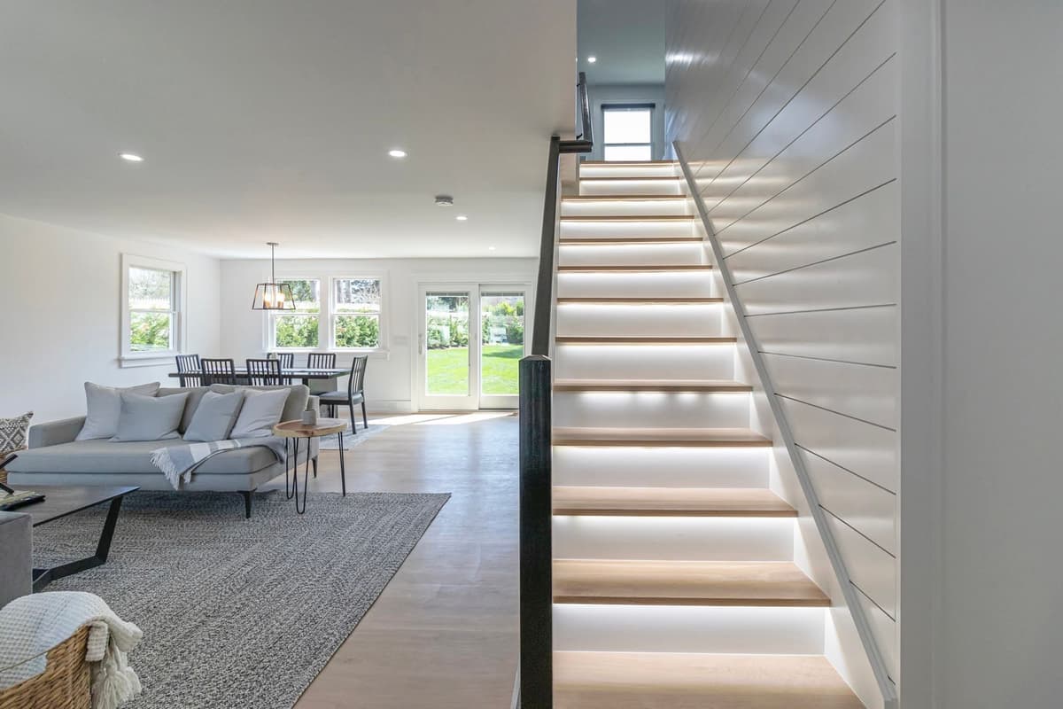 LED-lit staircase with shiplap wall, living and dining area with garden views beyond