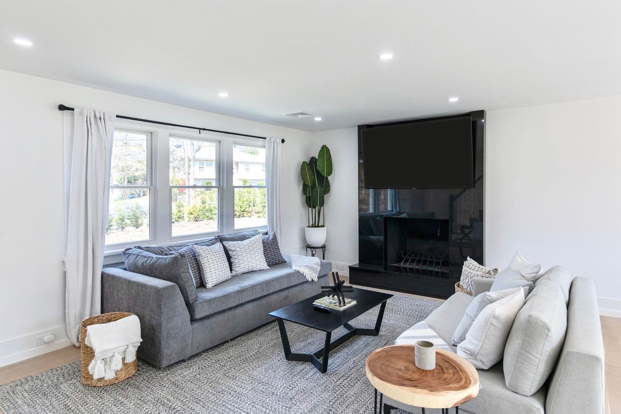 Living room with freshly painted white walls, black fireplace surround, and mounted TV