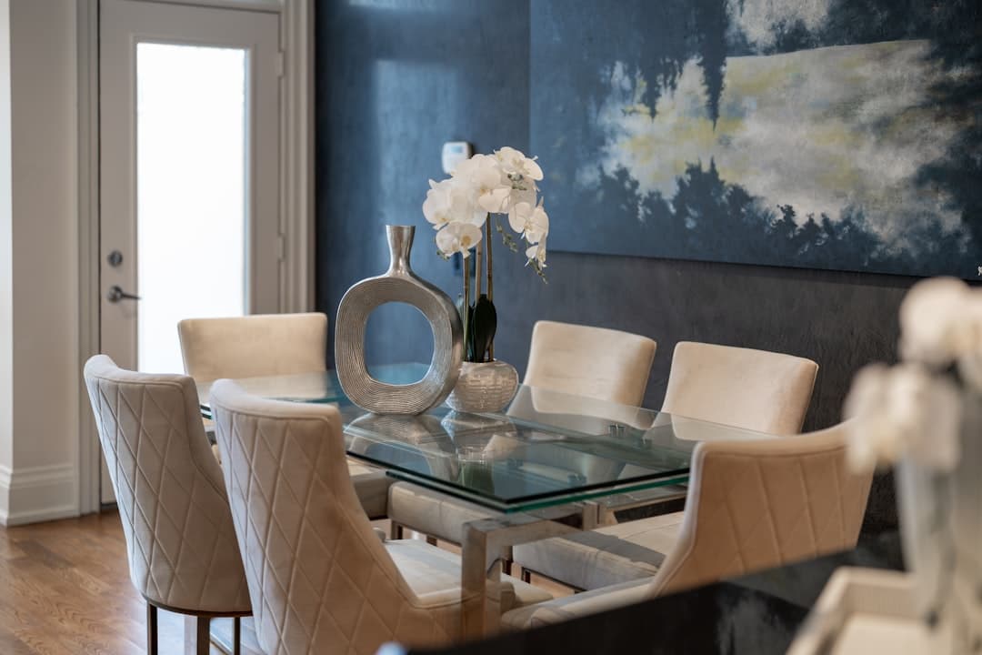 Elegant dining room with glass table and upholstered chairs in a beautifully painted interior
