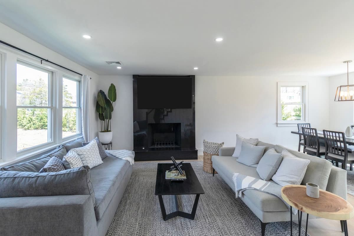 Spacious living room with black fireplace, dual sofas, and dining area with pendant lighting