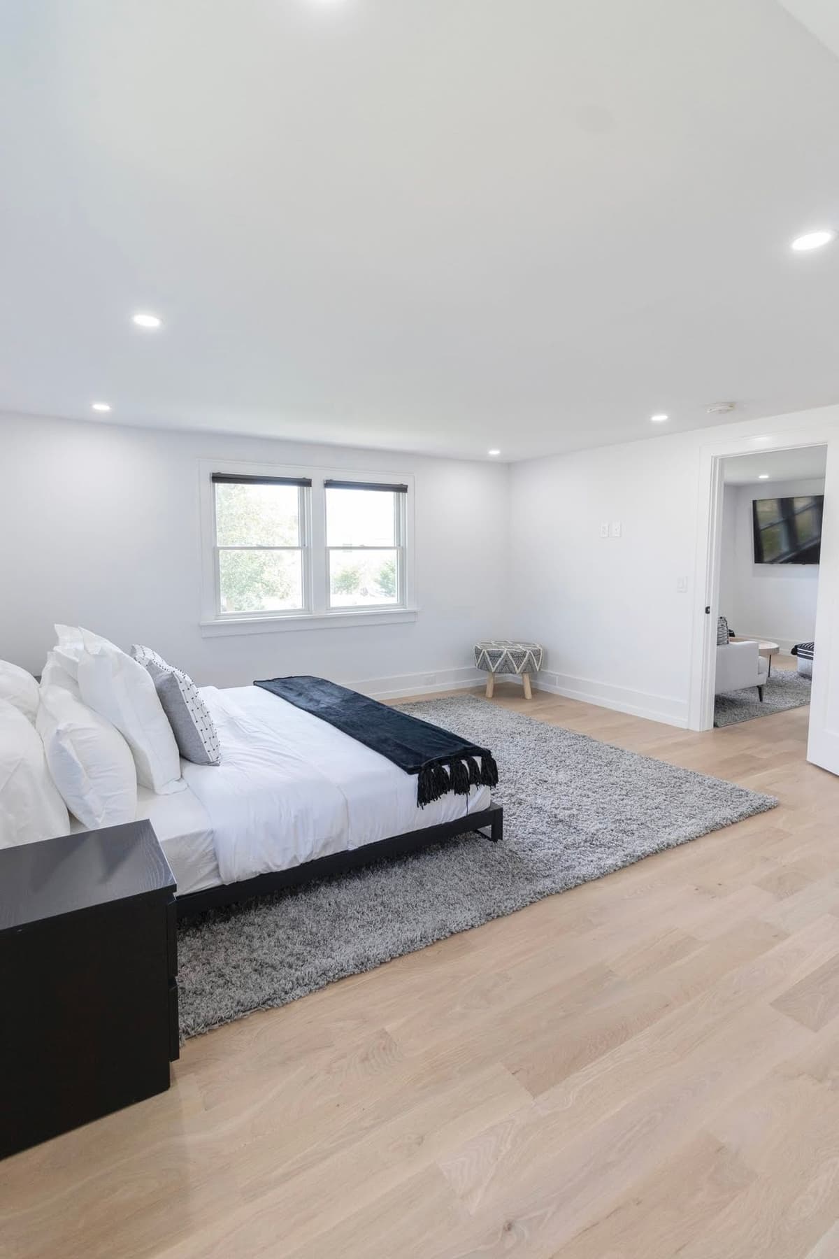 Spacious master bedroom with crisp white walls, platform bed, and light hardwood floors