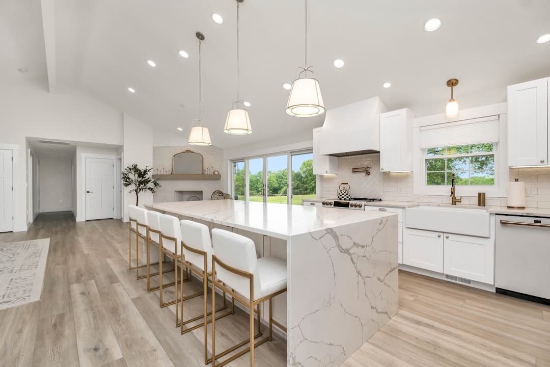 Spacious kitchen with marble island and smooth white cabinet finish
